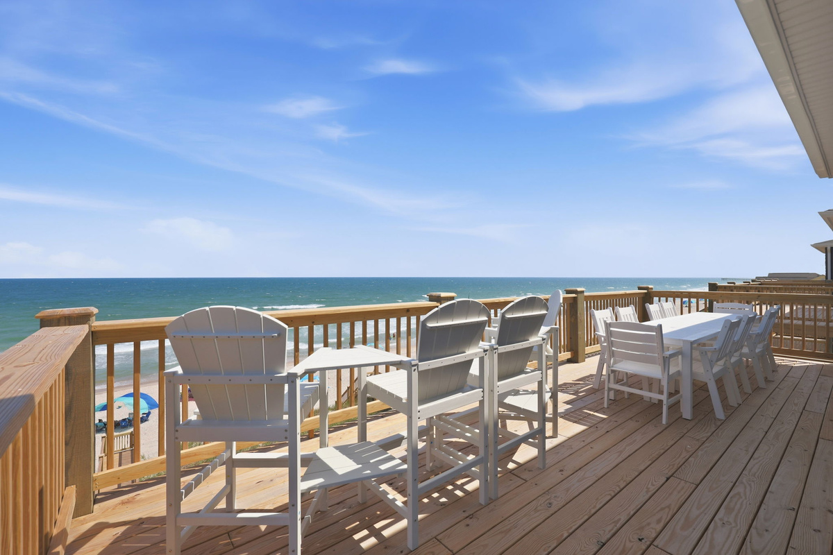 Oceanfront dining deck with seating and direct beach views