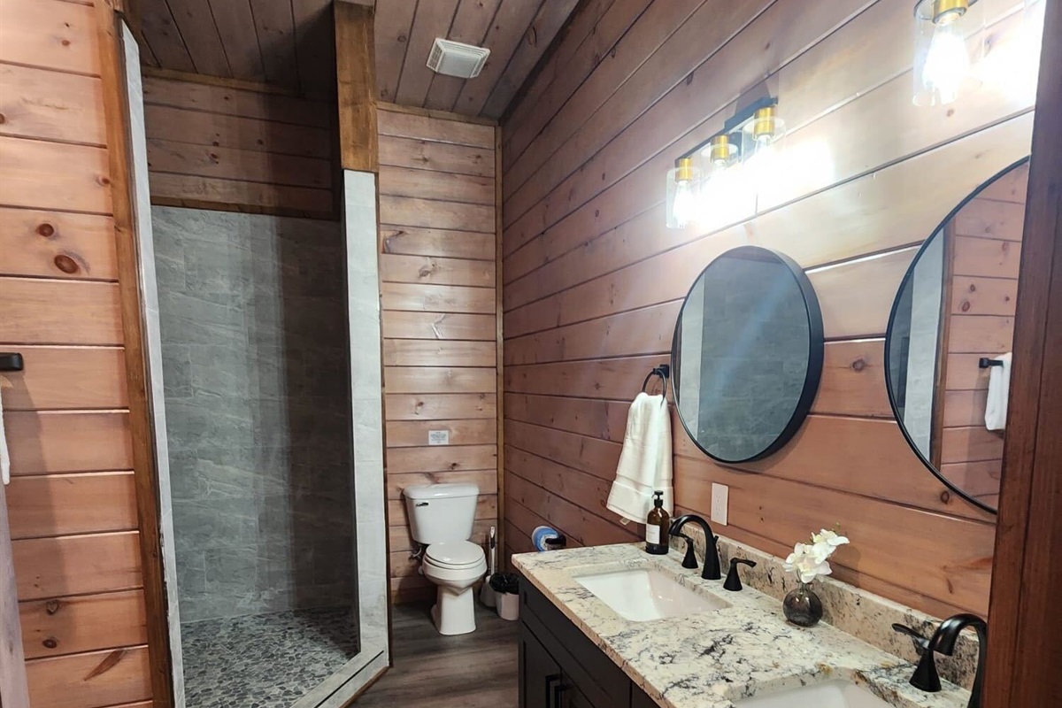 Modern walk-in shower with floor-to-ceiling tile and black matte fixtures.