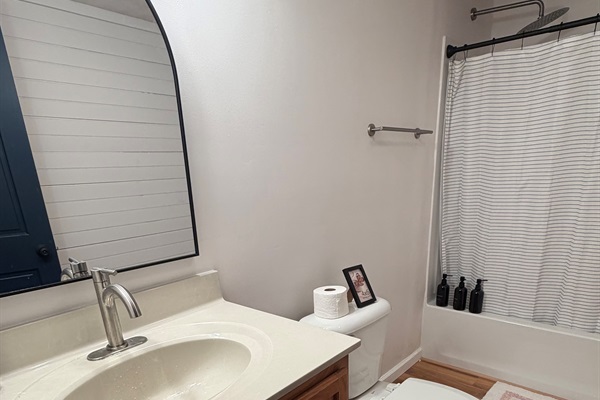 Light-filled lower-level bathroom with tub/shower combo and vanity—easy and comfortable for your stay.