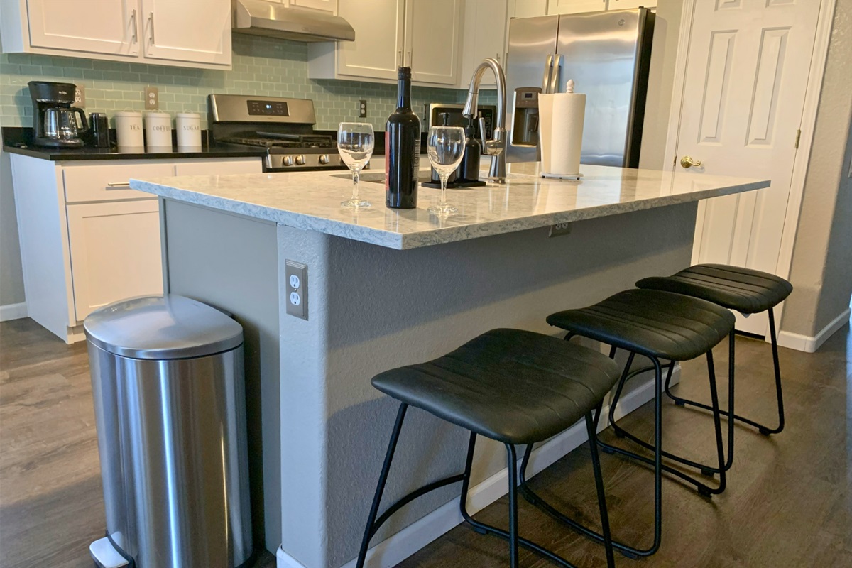 Sleek kitchen island with bar seating and stainless steel appliances — a perfect place for wine and conversation.