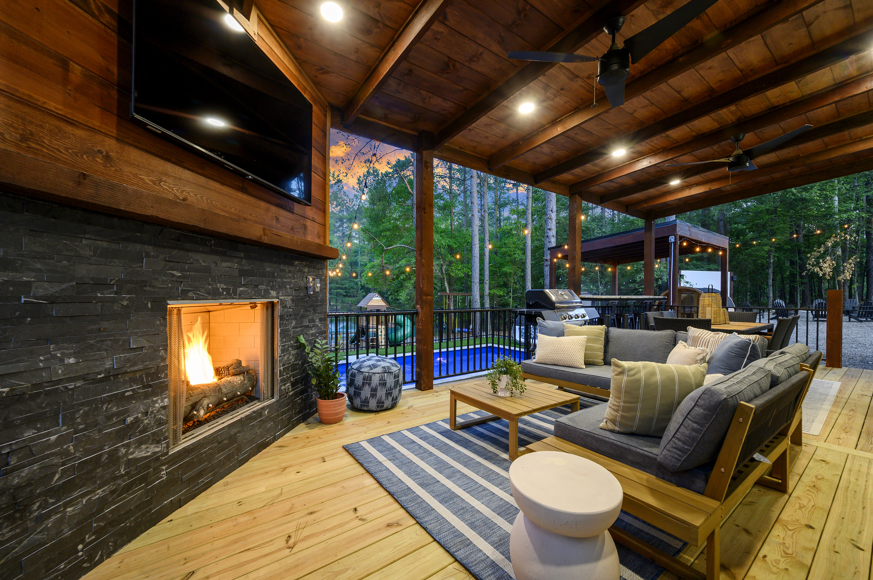 This is where everyone gathers. Settle in by the outdoor fireplace while staying connected to the pool, or grab a seat at the bar top overlooking the pool, playset, pond & pines beyond.