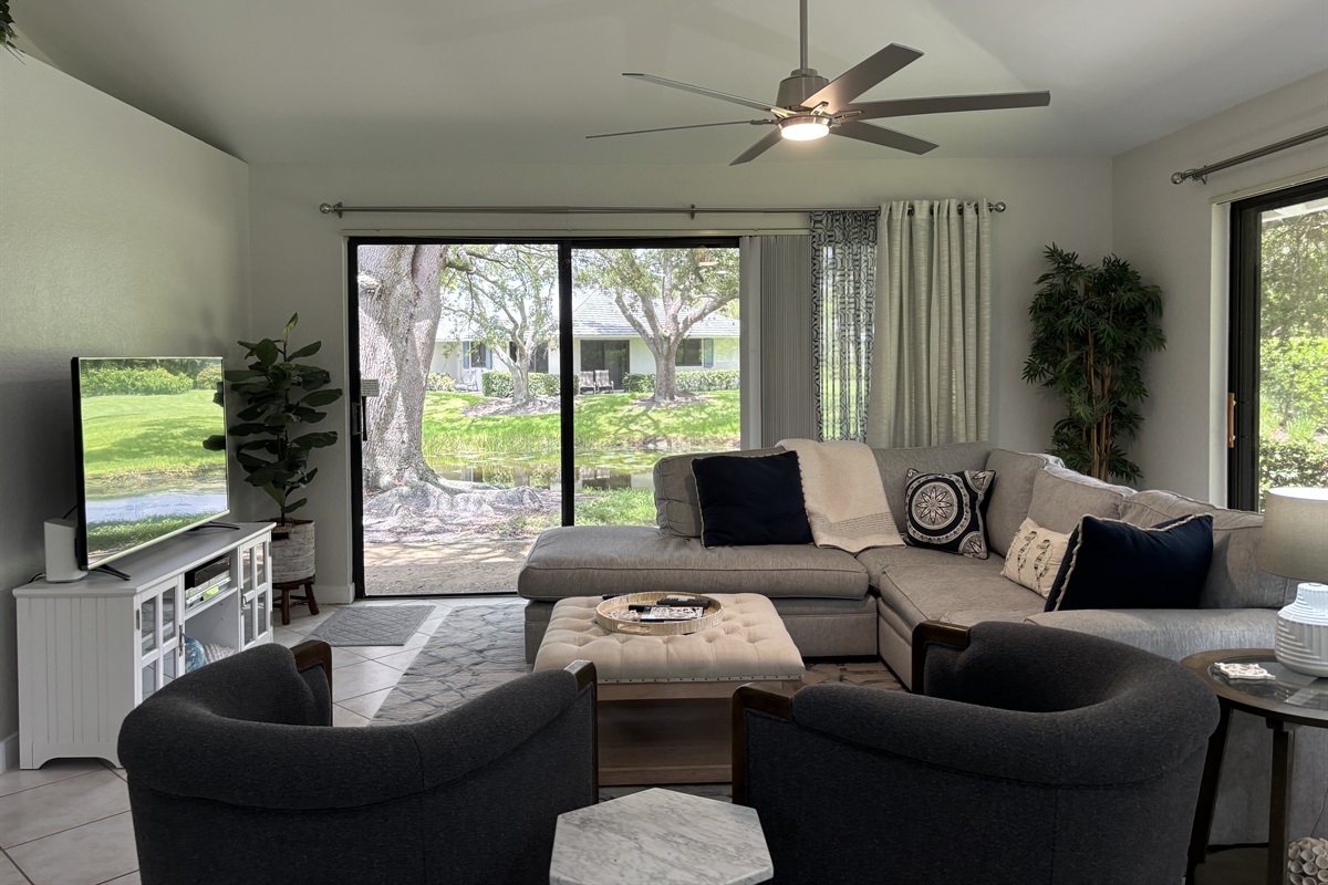 Our large, open living room has seating for six in front of the TV. Two large sliding glass doors let in plenty of light and views of the surrounding, peaceful landscaping.