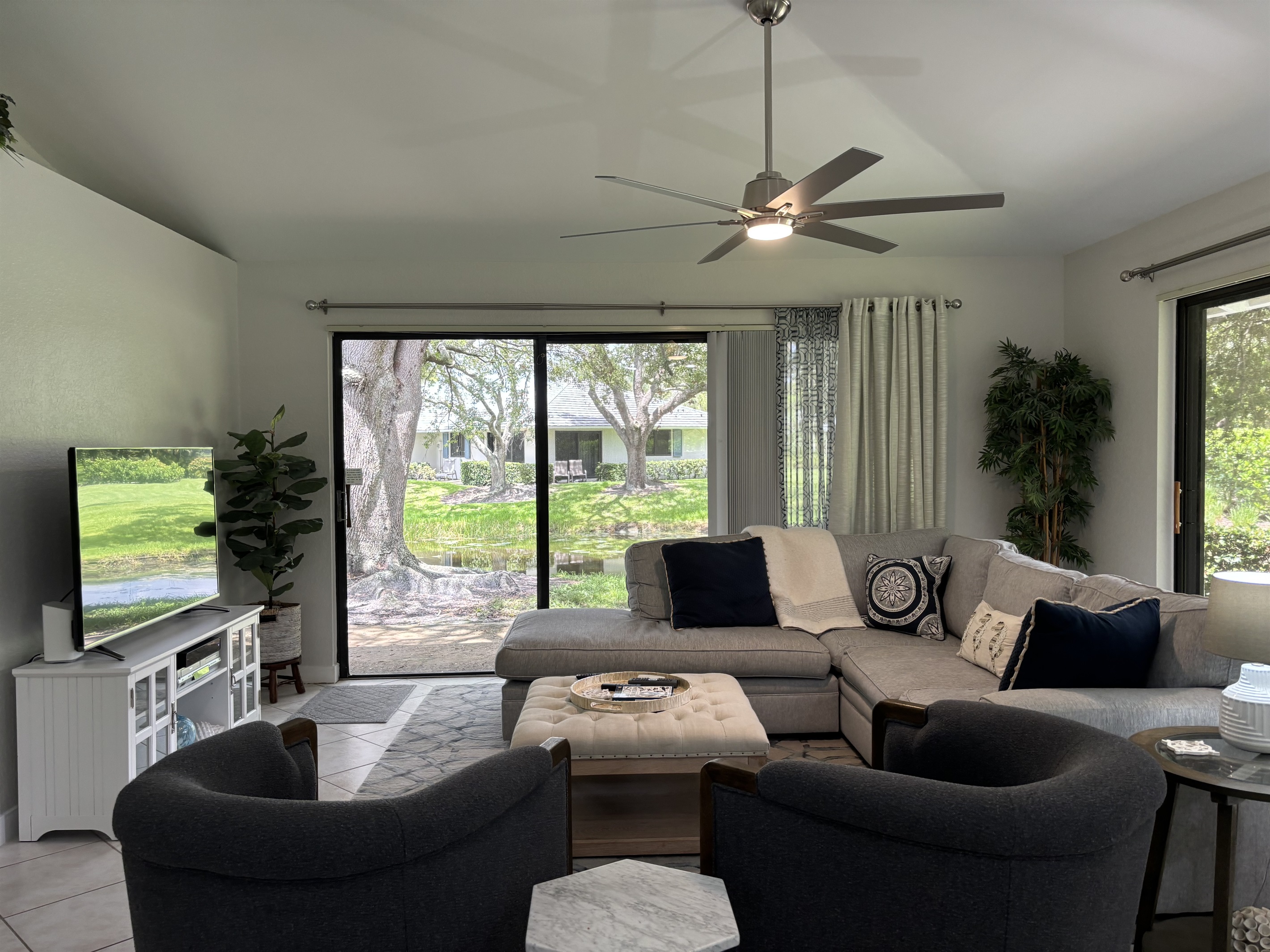 Our large, open living room has seating for six in front of the TV. Two large sliding glass doors let in plenty of light and views of the surrounding, peaceful landscaping.