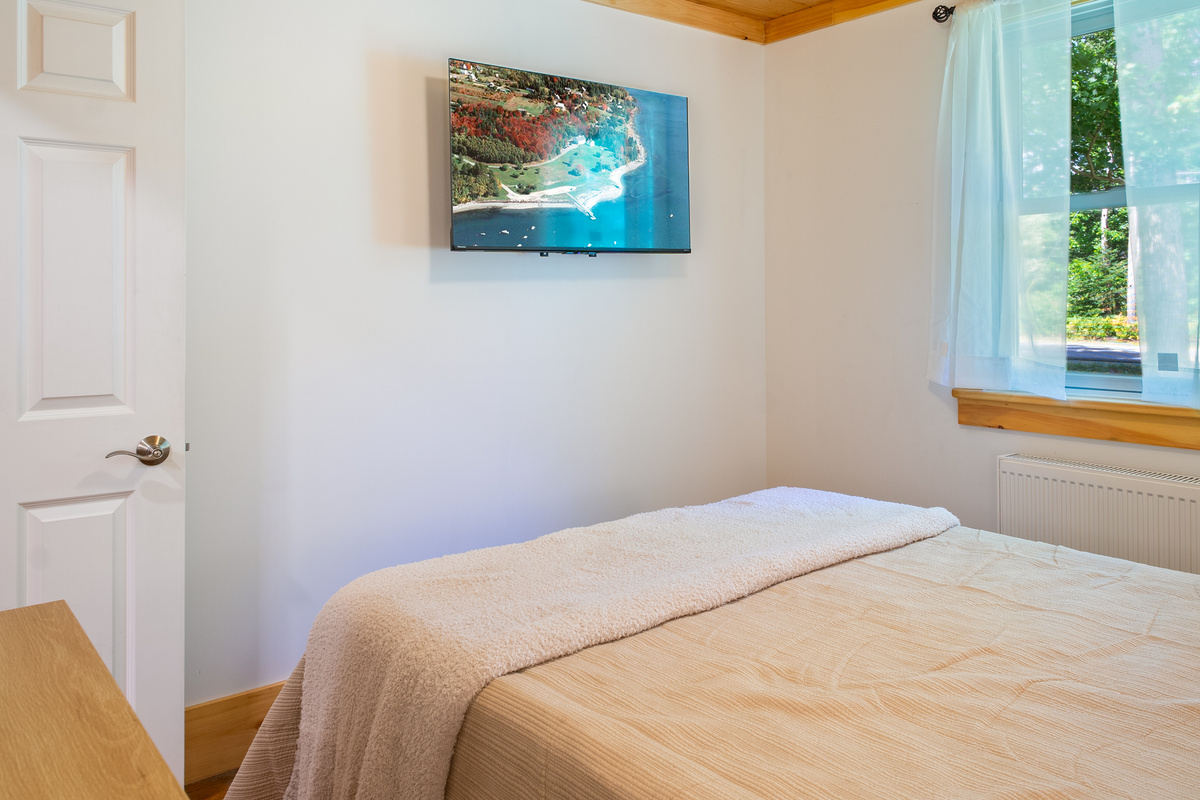 Catch up on your favorite movies from the comfort of bed with the wall-mounted flat-screen TV. Positioned directly across from the queen mattress, this layout ensures clear sightlines for effortless late-night entertainment and relaxation.