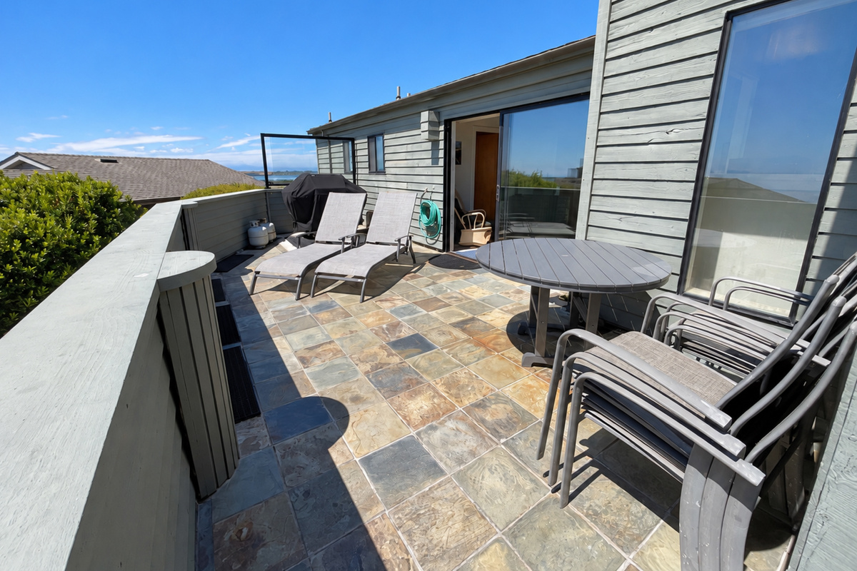 Deck facing Pacific Ocean South with Genesis Weber propane Barbecue and 2-lounge chairs.  Outdoor table with 5 chairs.