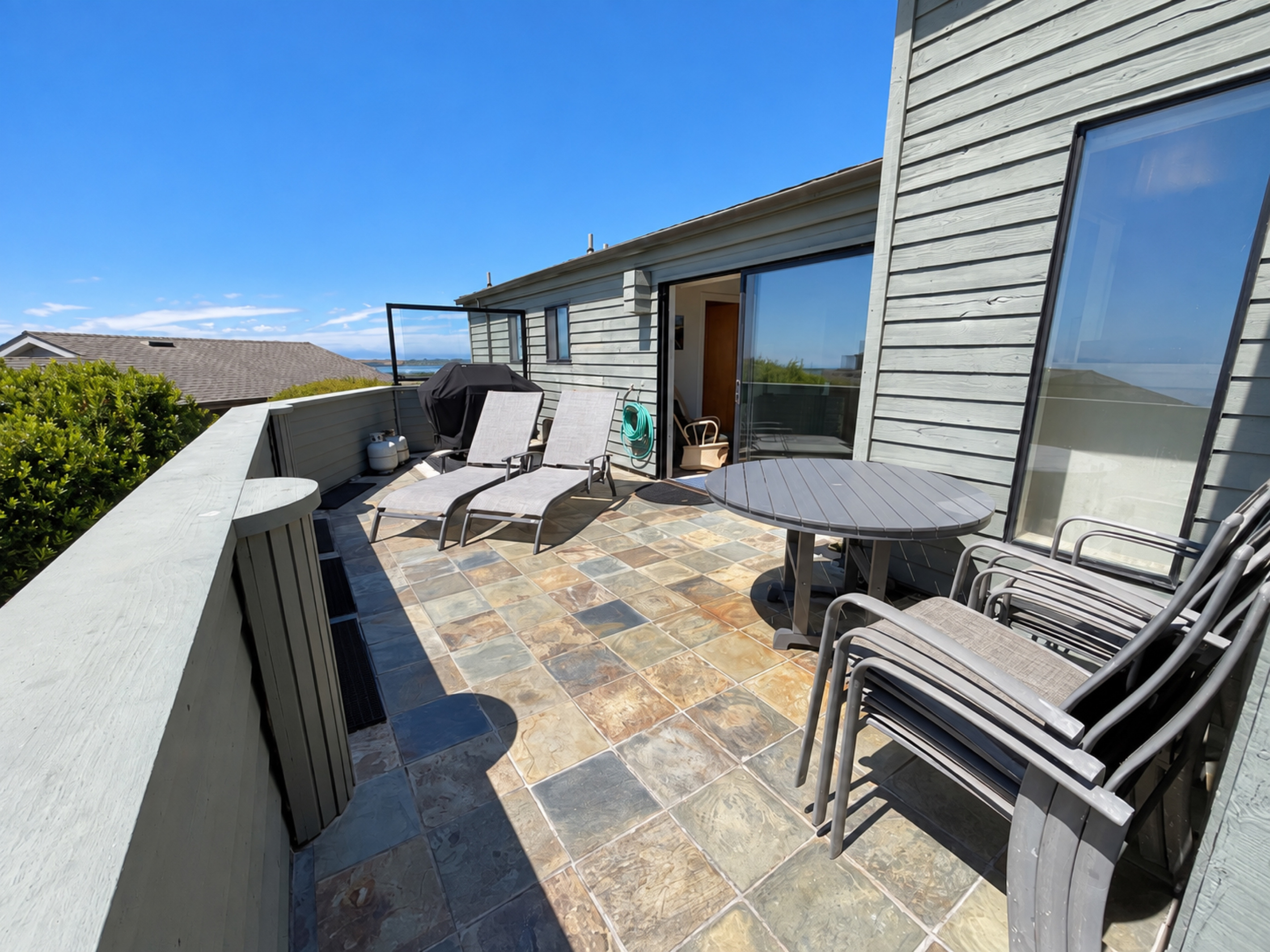 Deck facing Pacific Ocean South with Genesis Weber propane Barbecue and 2-lounge chairs.  Outdoor table with 5 chairs.