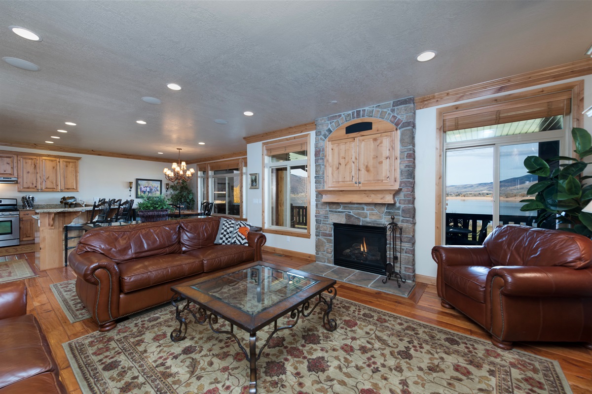 Warm and inviting living room with cozy leather seating, fireplace, and stunning lake views just beyond the windows.