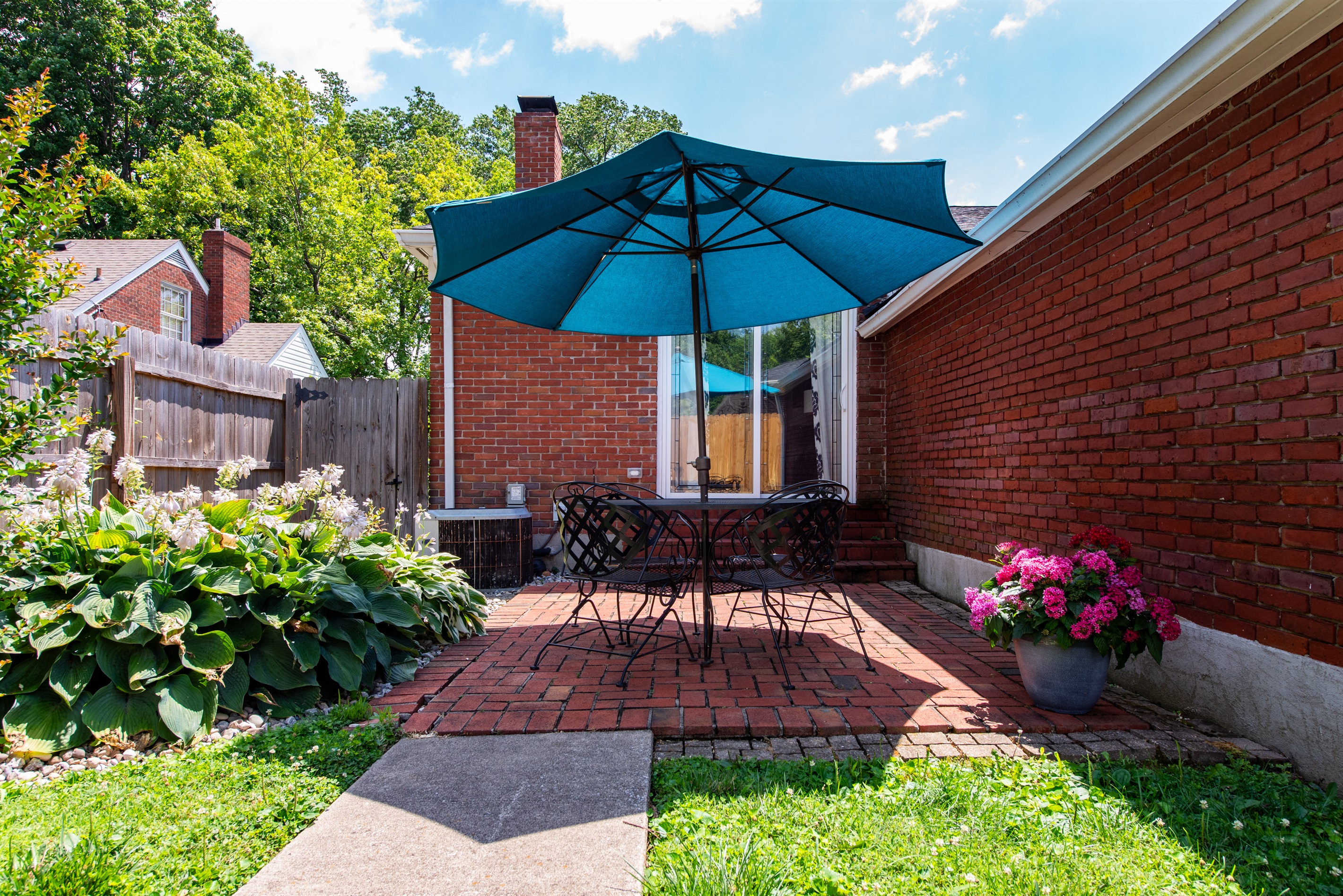 Unwind on this cozy backyard patio after a day on the Bourbon Trail! Enjoy a table, chairs, & teal umbrella on red brick paving with a privacy fence—perfect for sipping your favorite bourbon!