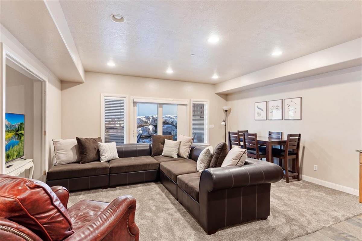 A stylish downstairs living room with plush sectional seating and abundant natural light—perfect for relaxing or gathering with guests.