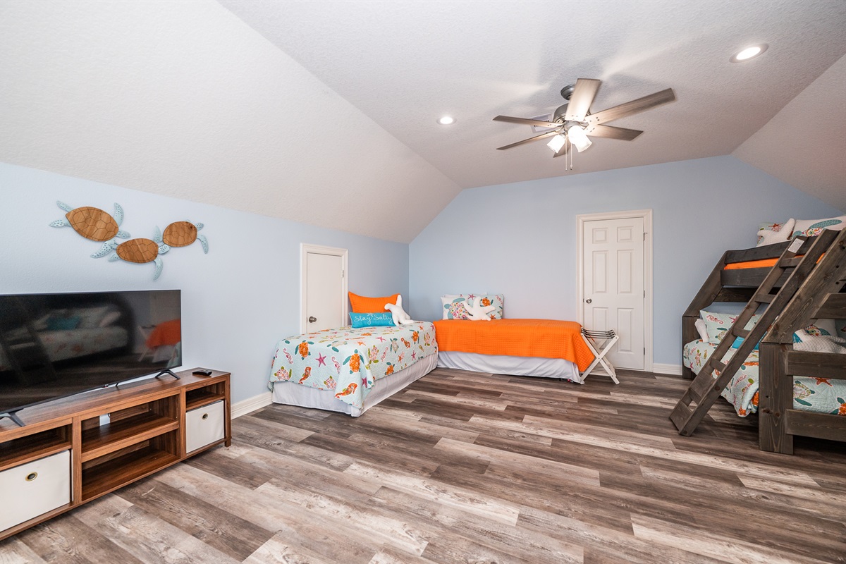upstairs huge loft area with twin over full bunk bed and 3 twin beds, half bathroom and smart TV