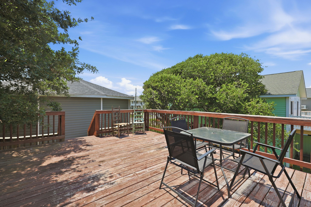 Private rear sun deck featuring outdoor dining and rocking chairs, a relaxing spot to enjoy the coastal breeze
