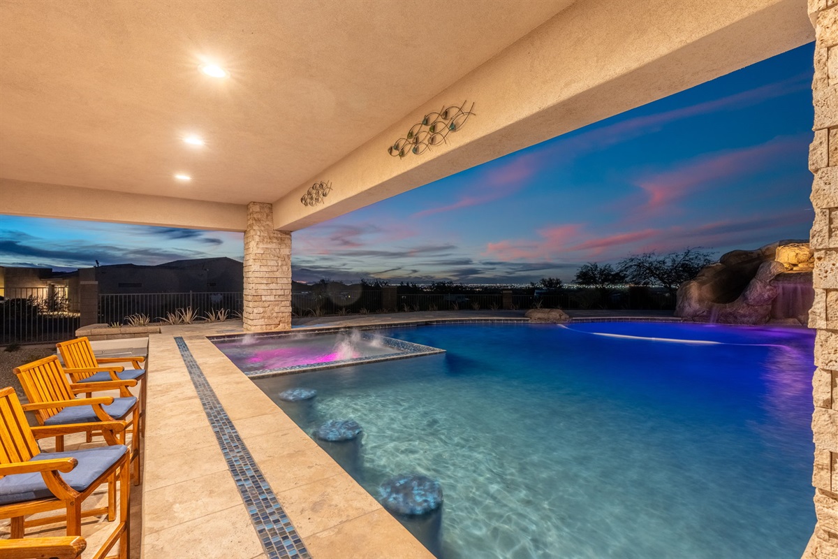 Covered patio lounge beside illuminated pool and spa — the ultimate space for sunset drinks and night conversations