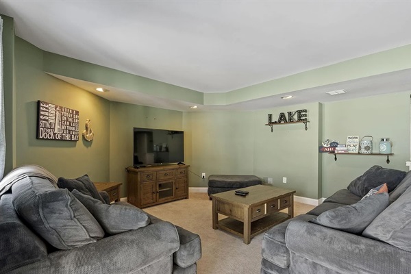 A cozy lower-level hangout featuring oversized seating and a large TV - ideal for movie nights and late-night gatherings.