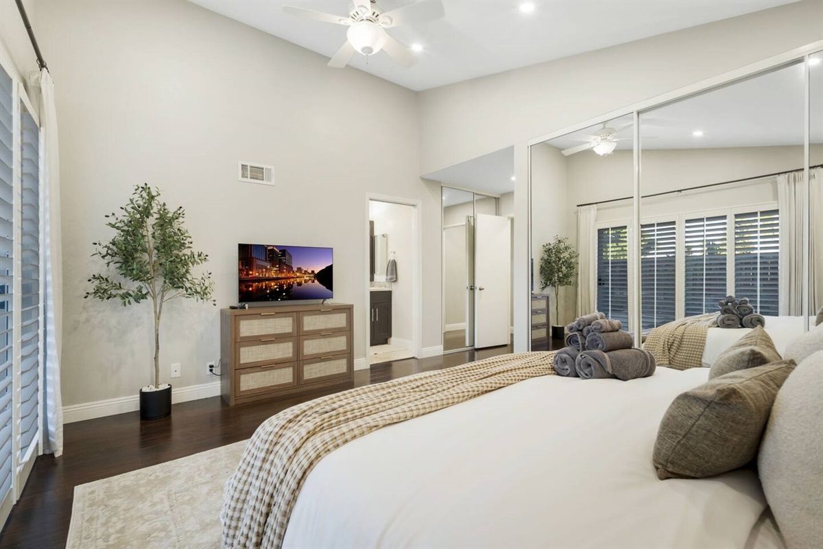 The primary bedroom features a cozy king bed, a 42" smart TV, and a sleek 6-drawer dresser. Two spacious closets with hangers offer ample storage, while the attached bathroom adds convenience. A perfect blend of comfort and style