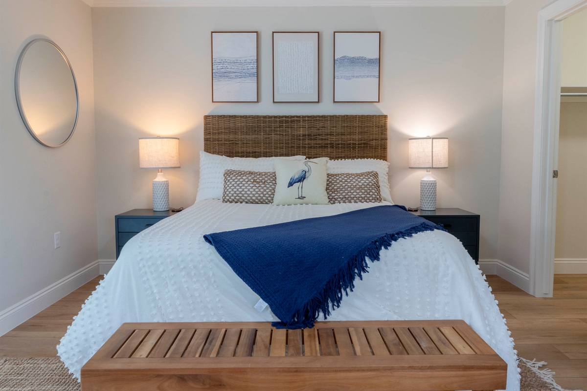 A cozy coastal bedroom with a rattan headboard, navy blue accents, soft lighting, and serene décor.