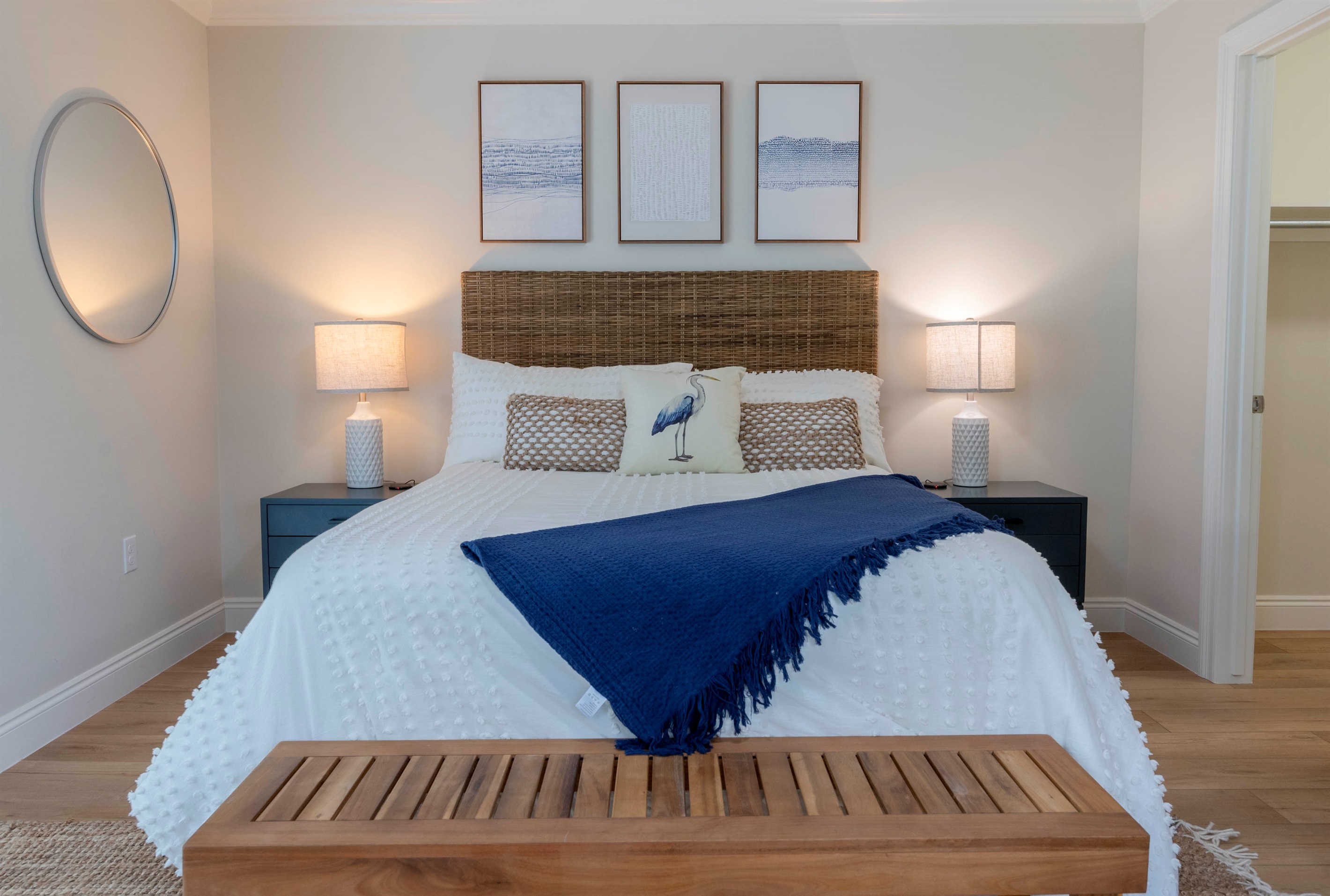 A cozy coastal bedroom with a rattan headboard, navy blue accents, soft lighting, and serene décor.