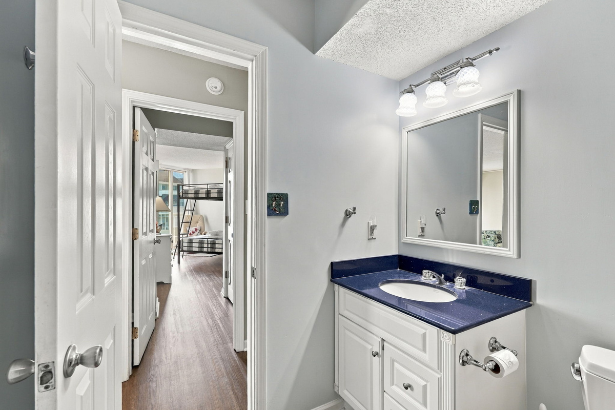 Bright, pristine bathroom featuring a bold blue vanity with plenty of space to get ready.