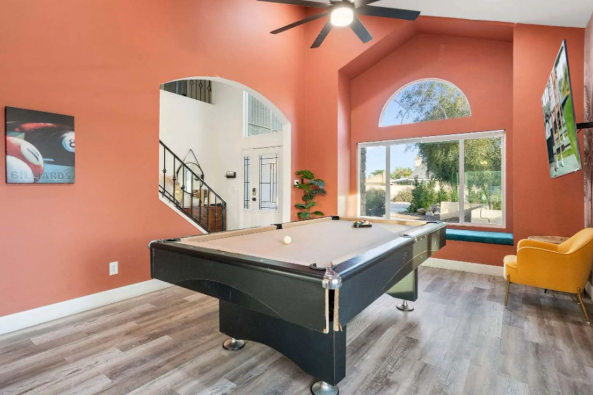 Recreation room with pool table, vibrant coral walls, arched entryway, and stunning outdoor views.