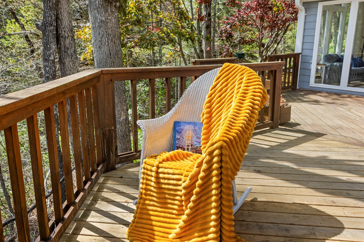 Deck Bliss: Relax in a stylish chair with vibrant throw, surrounded by nature's beauty!