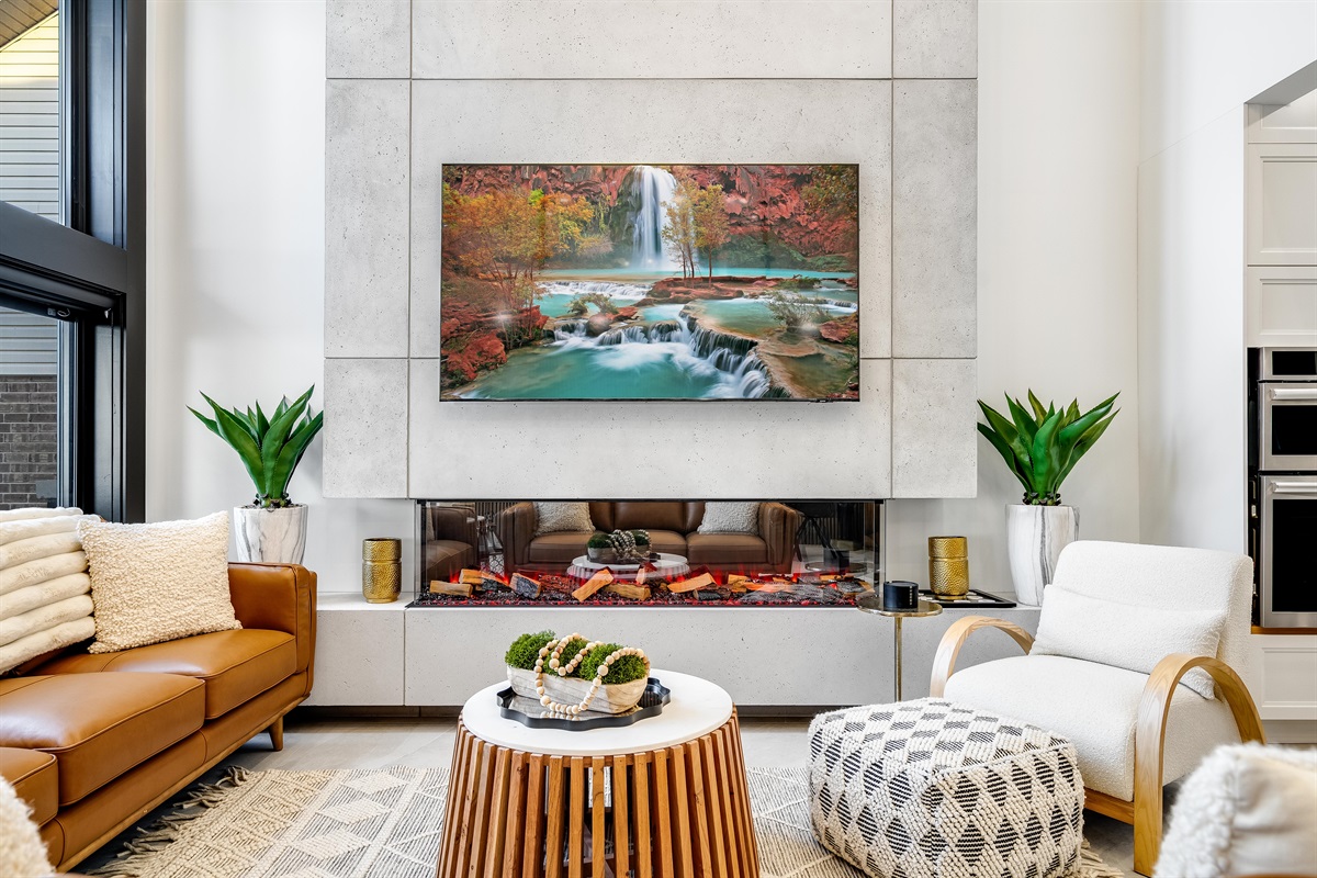 Living room with stunning lake views, vaulted ceilings, fireplace, smart tv, and modern furnishings and décor.