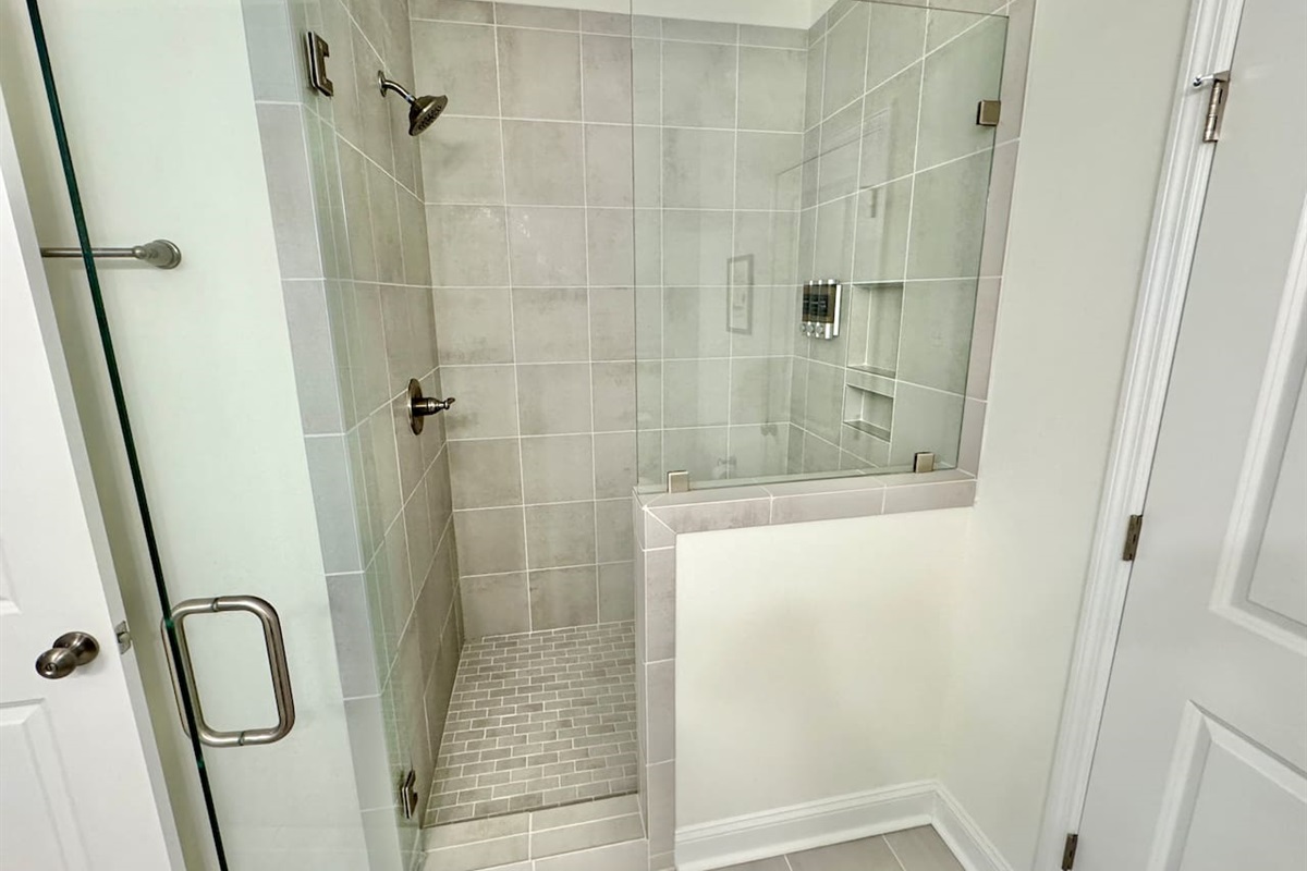 Master bathroom has a ceiling-to-floor tile shower with glass enclosure and 2 sinks.