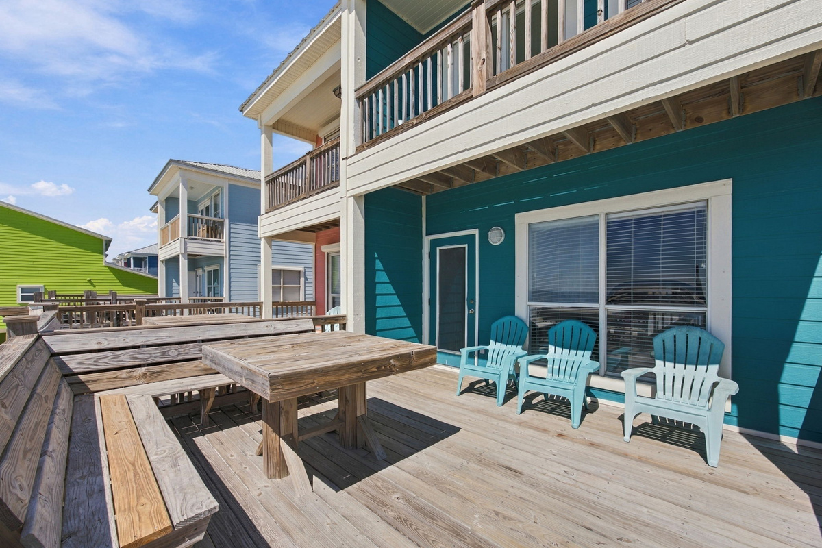 Outdoor dining and lounging area beside the vacation home, featuring a large table, comfortable chairs, and a private pool area nearby.