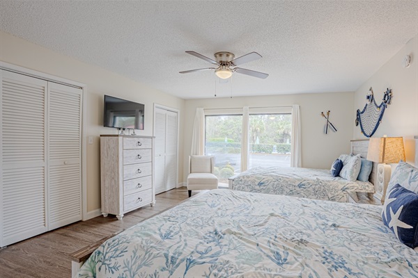 Guest bedroom with two queen beds, ceiling fan, and smart TV