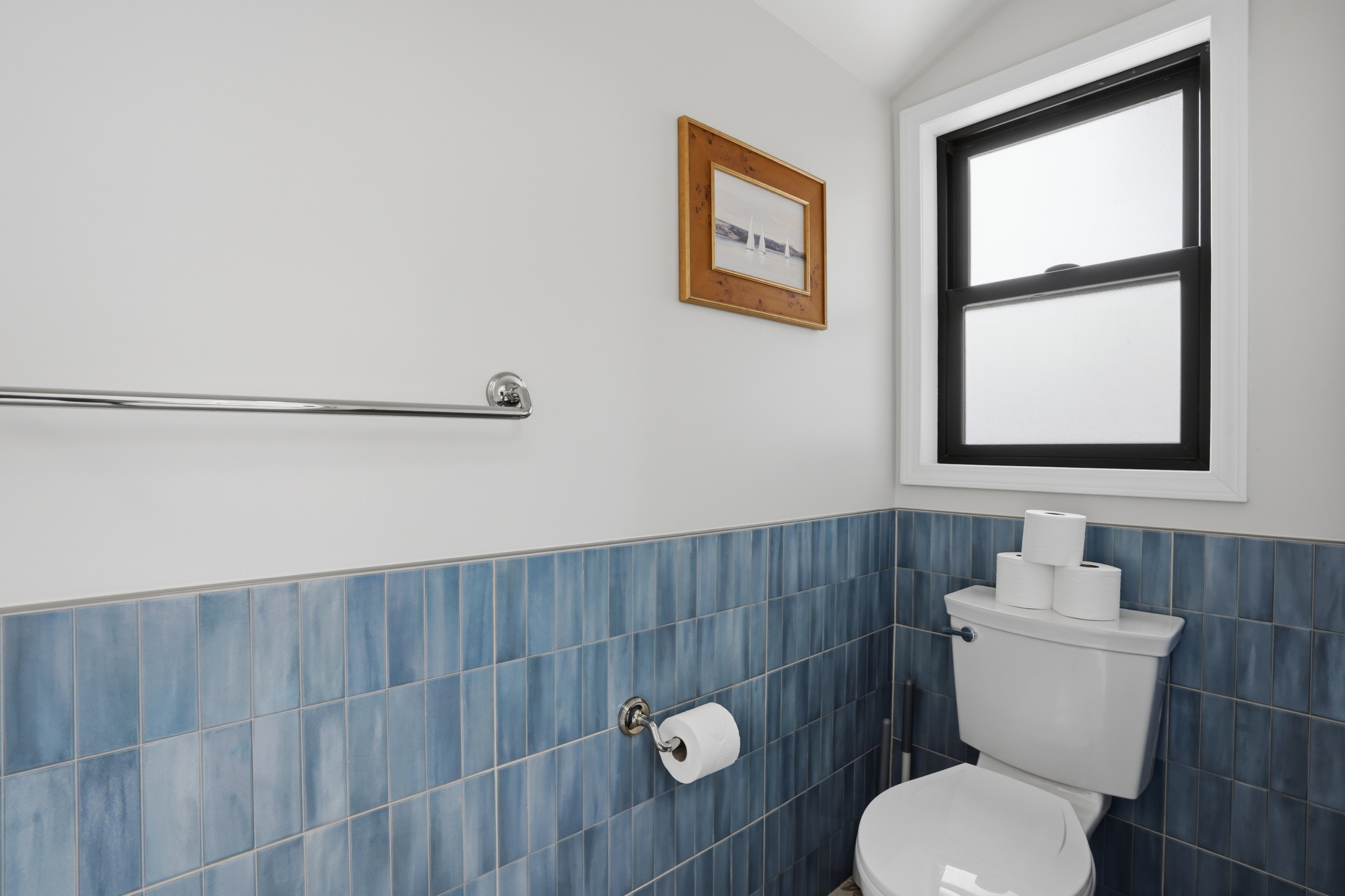 Clean, modern bathroom with blue tile accents, sleek fixtures, and a bright, minimalist design. Fresh and functional space with a hotel-like feel, offering comfort and simplicity for guests.