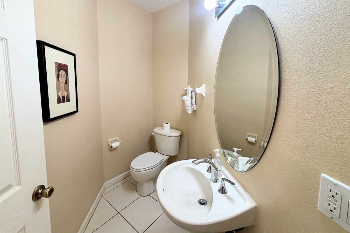 Convenient half bathroom with pedestal sink, tile flooring, and clean, neutral finishes.