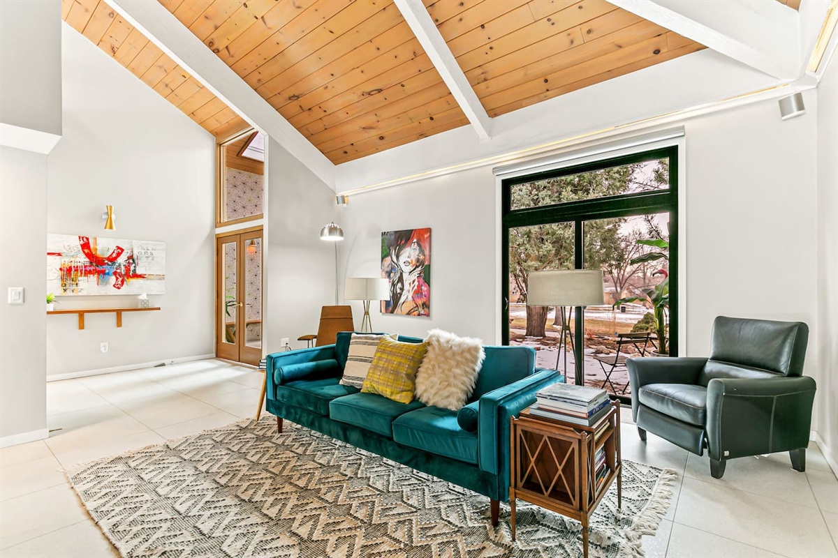 Welcome to the enchanting Living Room, furnished with a velvet sofa for intimate conversations, a two-sided fireplace, and easy access to the outdoor area, kitchen, and patio.