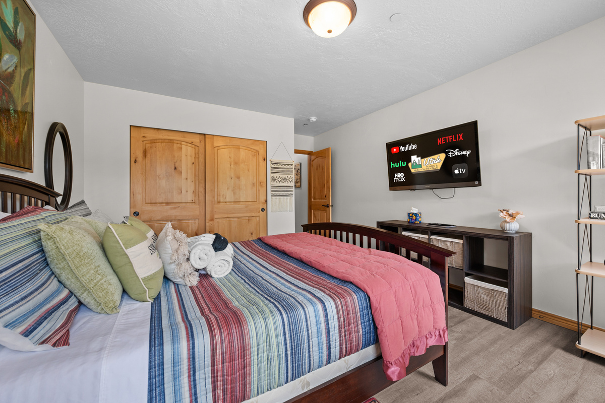 This inviting master bedroom offers a comfortable queen bed with fresh linens, charming decor, ample closet space, and soft lighting for a restful stay.