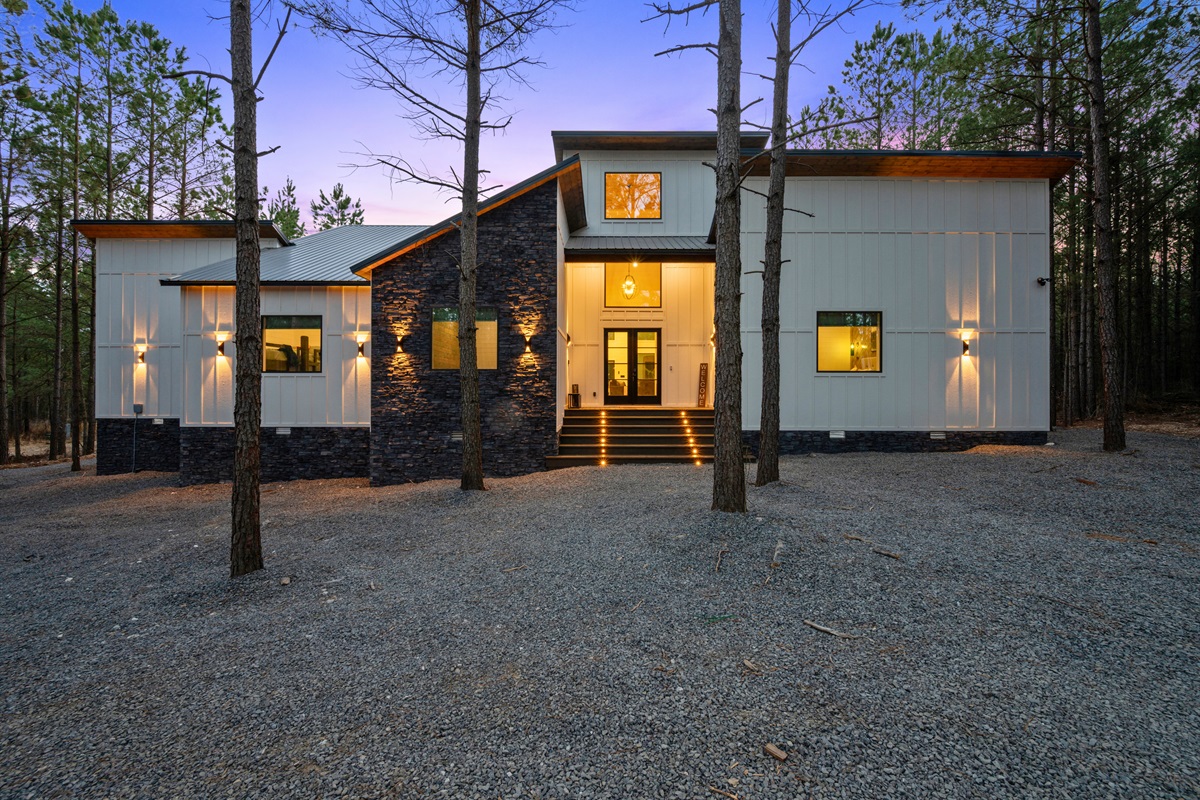 The front of the home welcomes guests with clean architectural lines, warm lighting, and a spacious entry area.