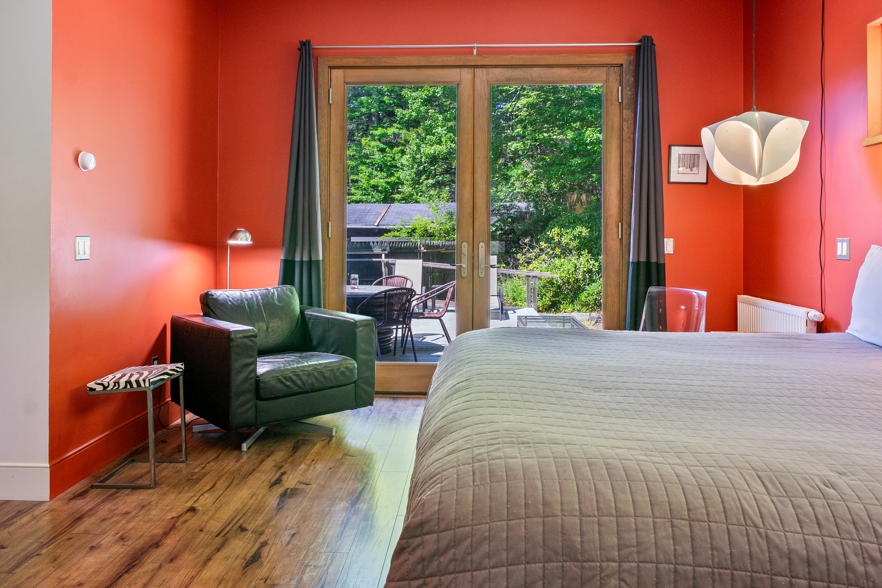 The primary suite features a cozy leather armchair and direct access to the 33ft deck through oversized French doors. This seamless indoor-outdoor flow allows you to enjoy the fresh Acadia air and the sounds of the forest right from your bedroom.