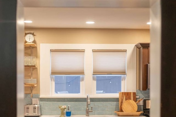 Thoughtfully designed for the home chef, this hallway opens into a modern kitchen featuring quartz countertops, stainless steel appliances, and a comprehensive selection of cookware.