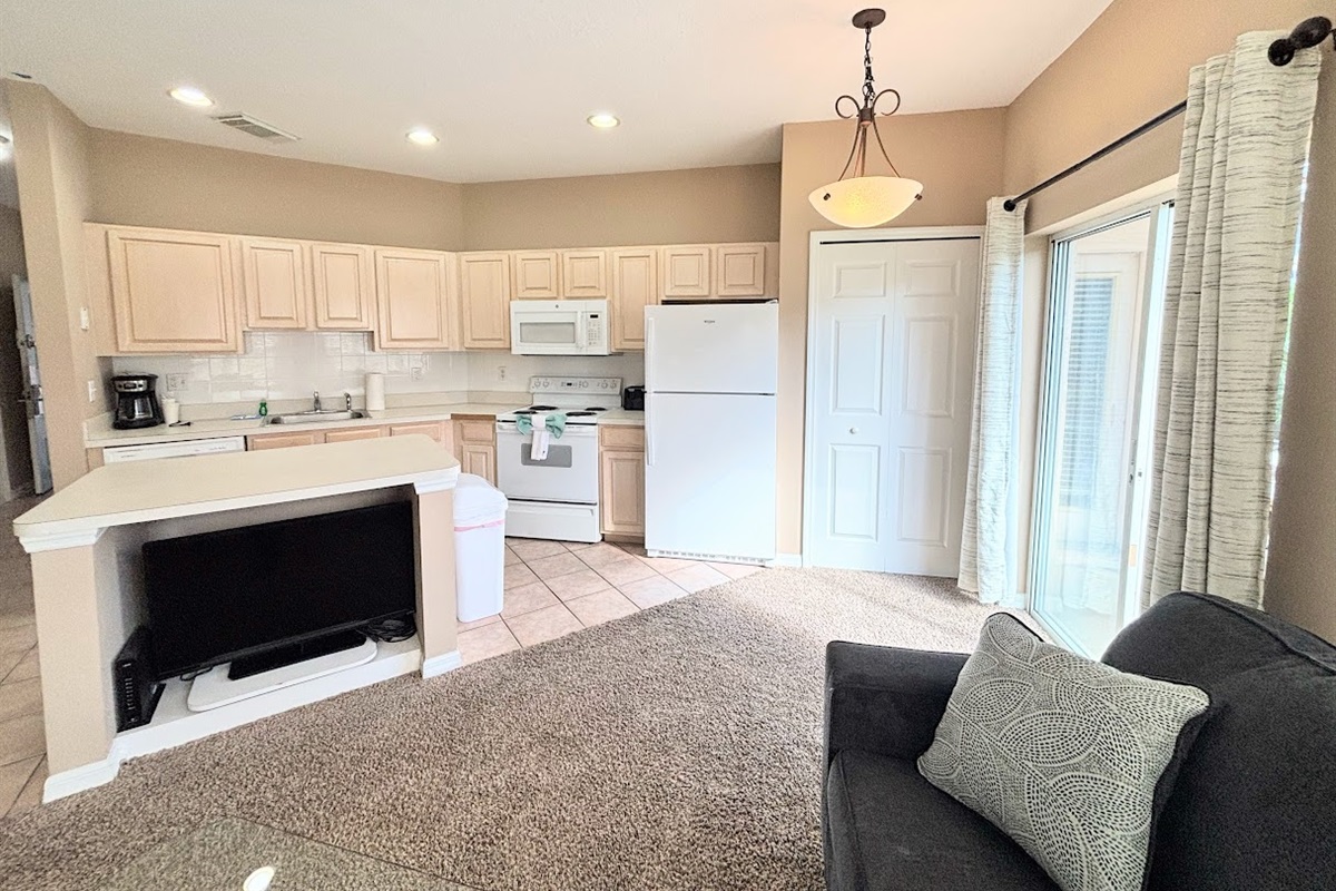 Open kitchen and living space featuring full-size appliances, breakfast bar seating, and easy access to the screened patio.