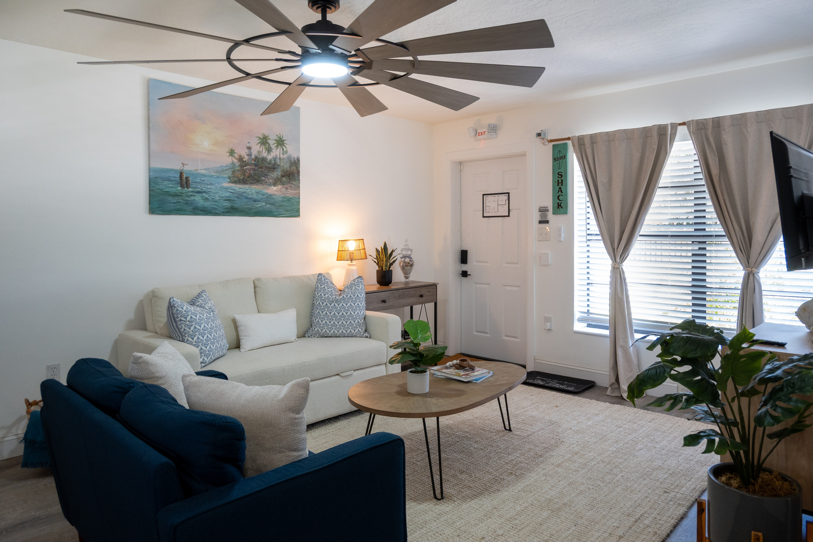 Bright living room with two sofas (one a sleeper for guests three and four) and coastal art