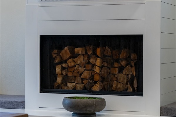 The fireplace’s built-in storage for firewood adds both practicality and a rustic decorative element.