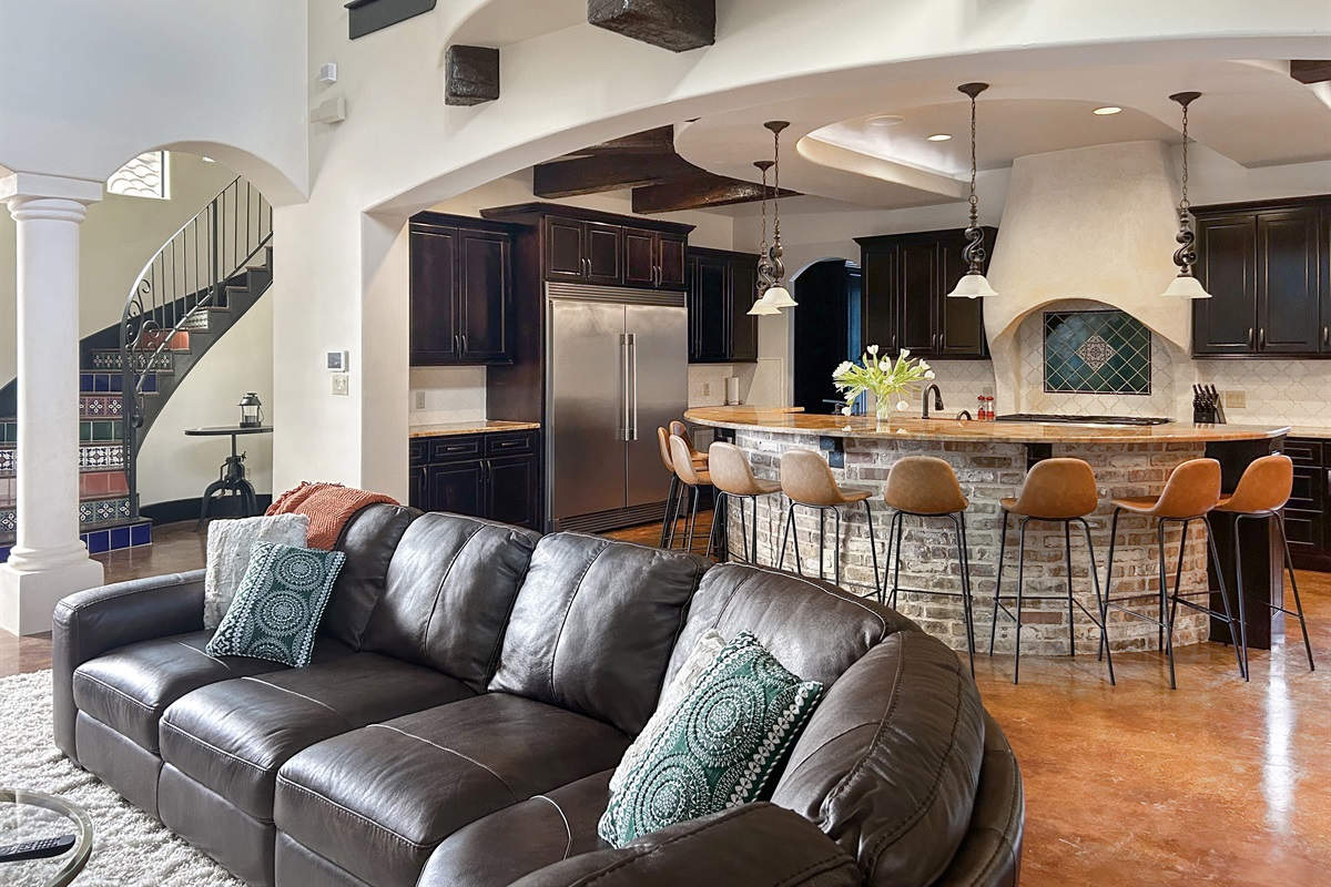 "Welcome to the heart of the house! This spacious living room boasts over 20-foot ceilings, abundant seating, a cozy fireplace, and a smart TV—all with stunning views of the resort-style pool.