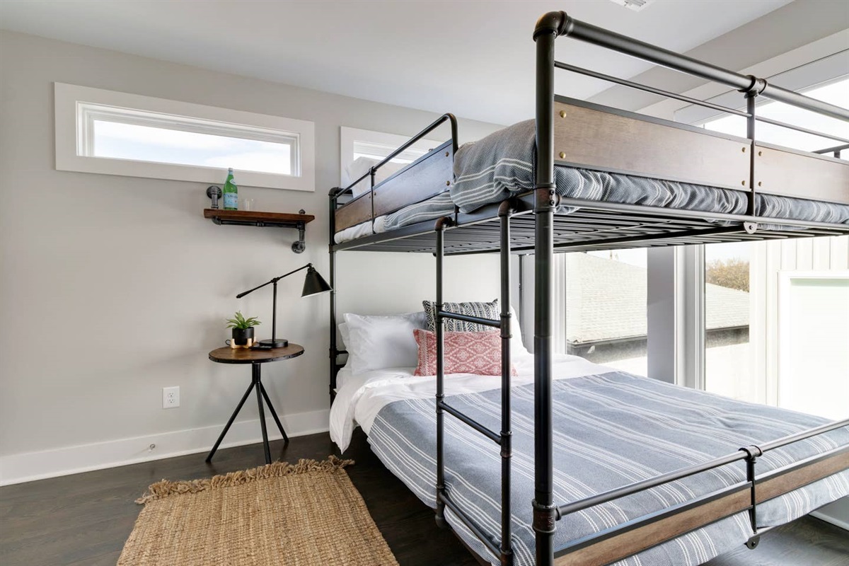 - Industrial style bunk bed with full size bottom and twin top for flexible sleeping - Large windows bring in natural light, brightening this cozy guest space - Thoughtful details like a side table, lamp, and shelf enhance comfort and charm