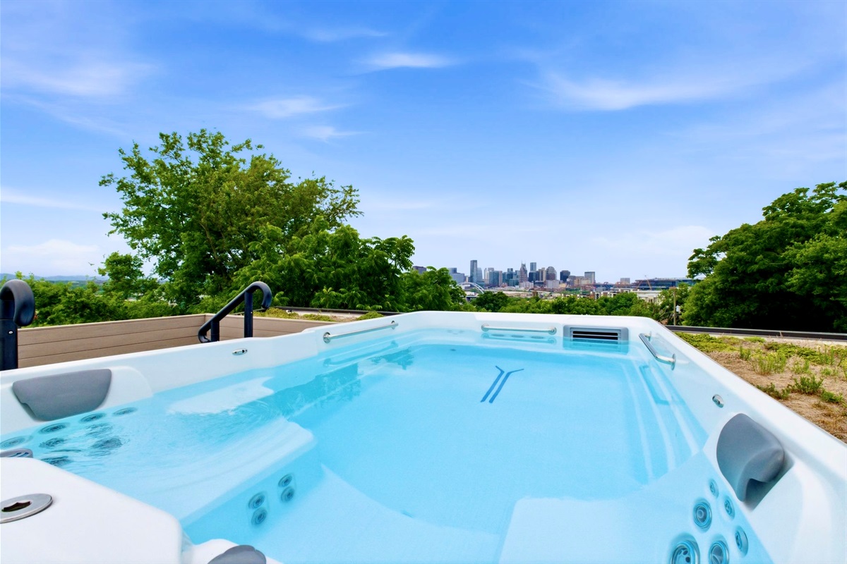 Sparkling hot tub surrounded by lush trees & open sky, perfect for a long, restorative soak.
