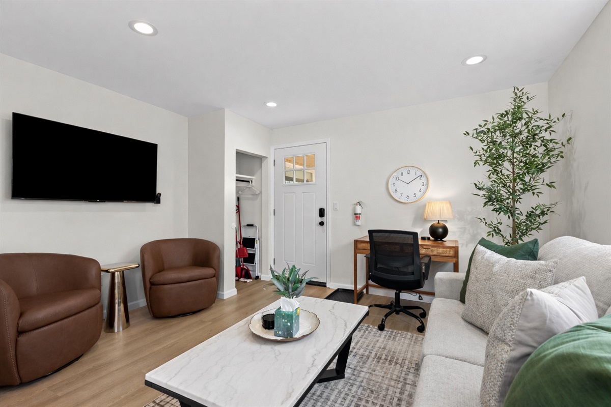 Comfortable living area with smart TV, cozy seating, and a dedicated workspace—bright, welcoming, and thoughtfully designed for work or relaxation.