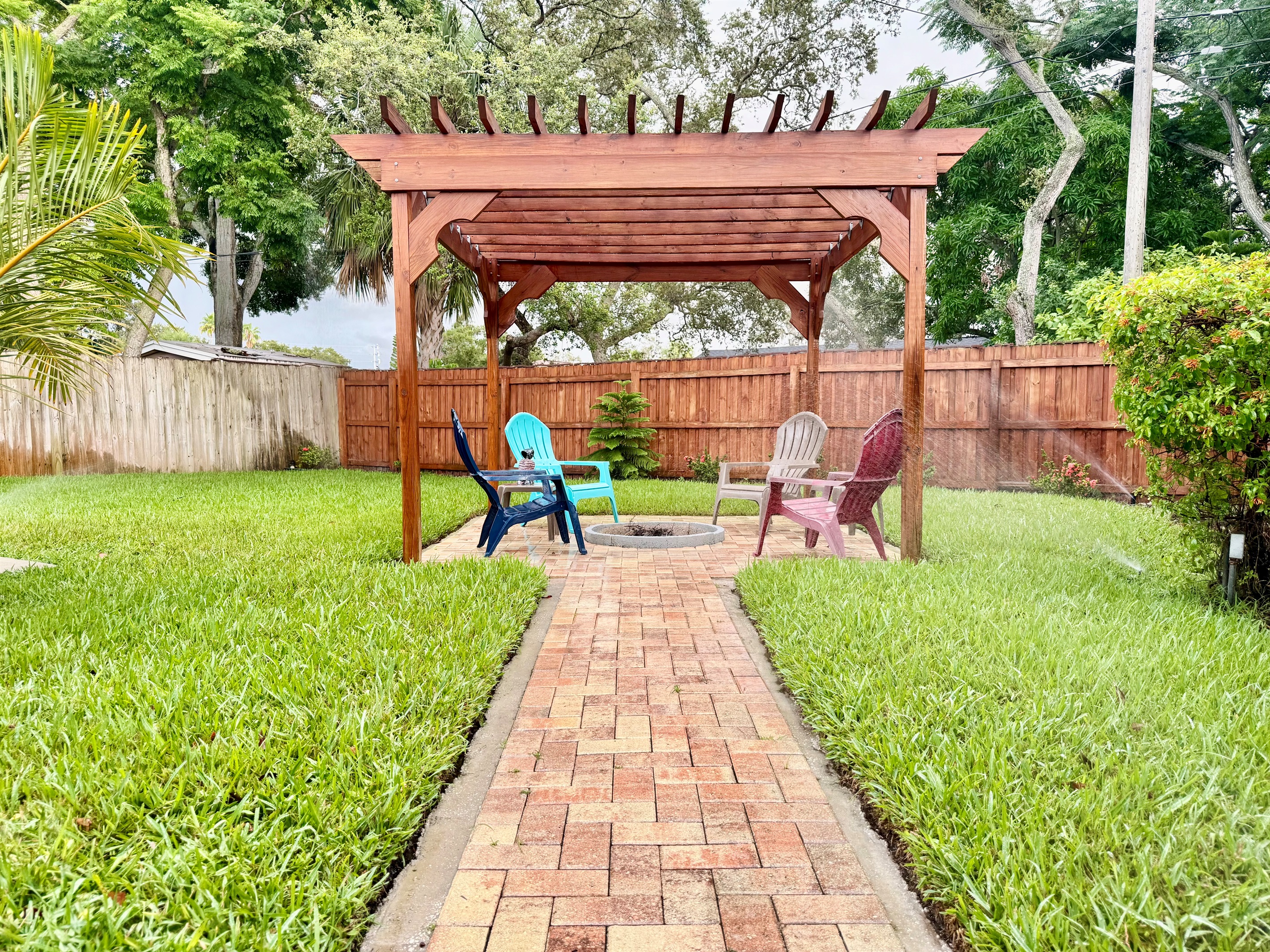 The perfect blend of natural wood, paver flooring, and cozy seating—this pergola space was made for memories.