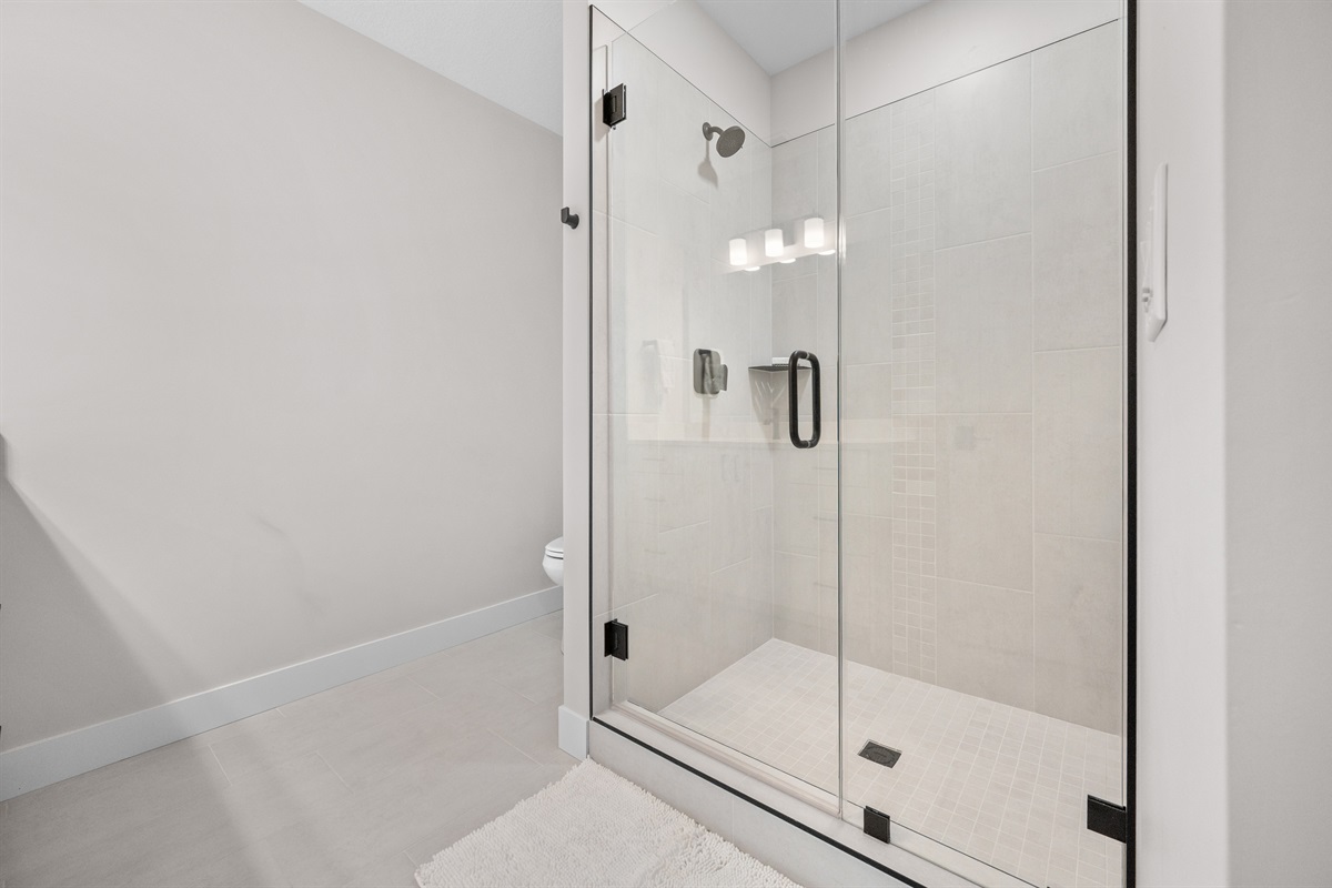 Private ensuite bath with sleek glass walk-in shower.