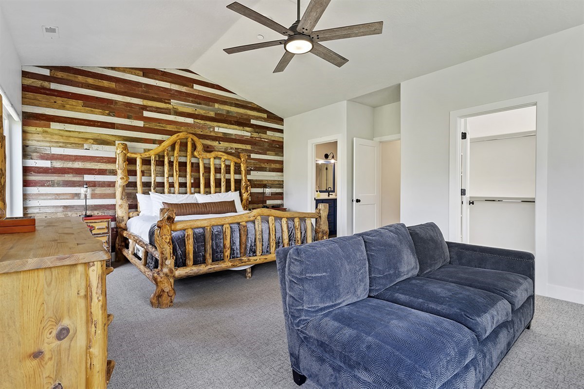 Escape to a luxurious primary suite featuring a king bed, artisan-crafted details, and a serene sitting area designed for ultimate relaxation.