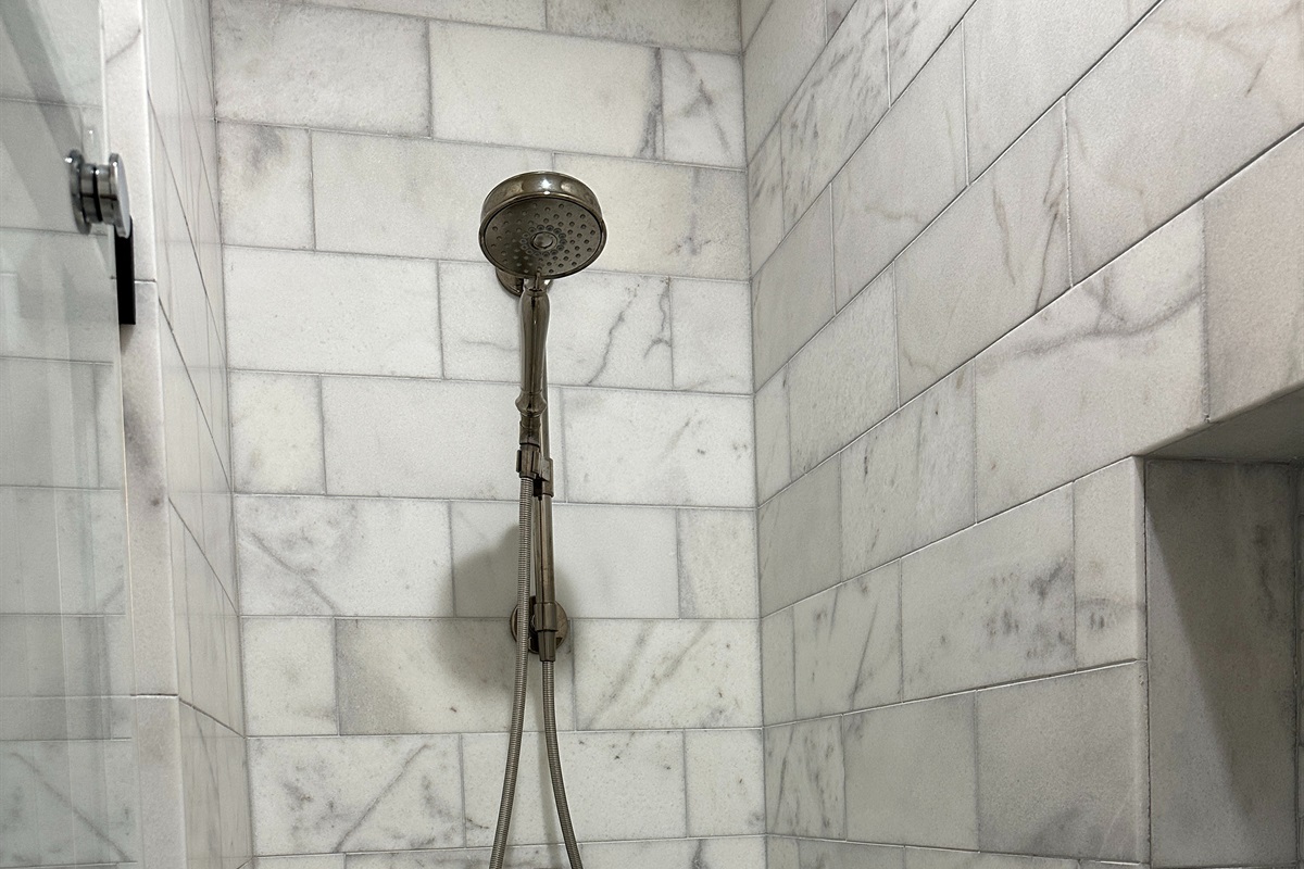Marble shower with glass door, shower wand with provided Bath & Body Works shampoo, conditioner and body wash
