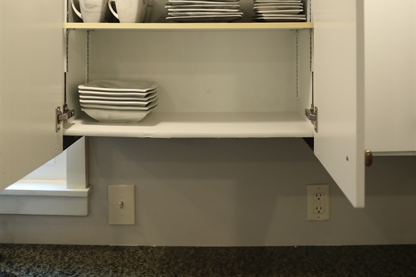 Kitchen cabinet showing grey marble plates, cups, and bowls