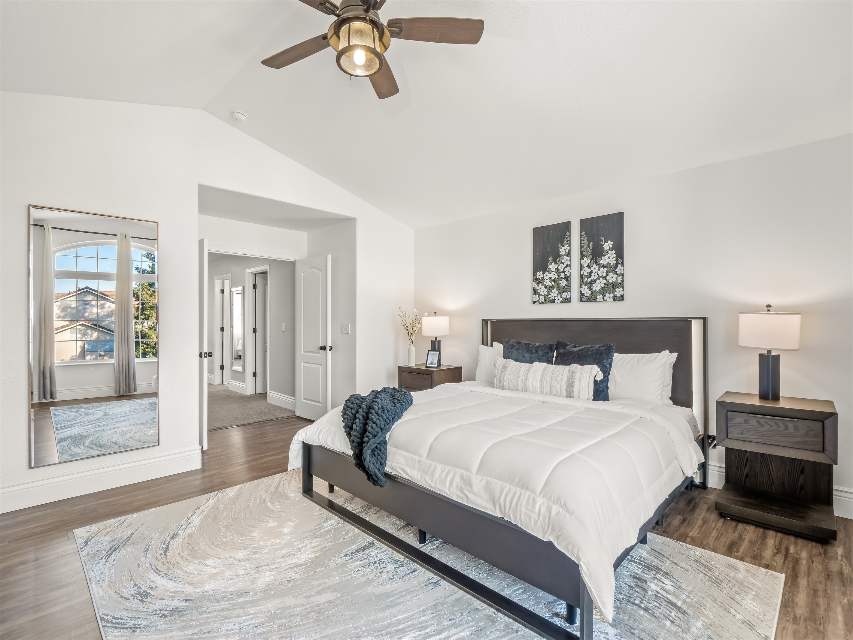 Spacious and light-filled primary bedroom featuring vaulted ceilings, a king bed, mounted TV, and a private en-suite bath. The oversized layout offers room to relax, unwind, and enjoy a true retreat feel during your stay.