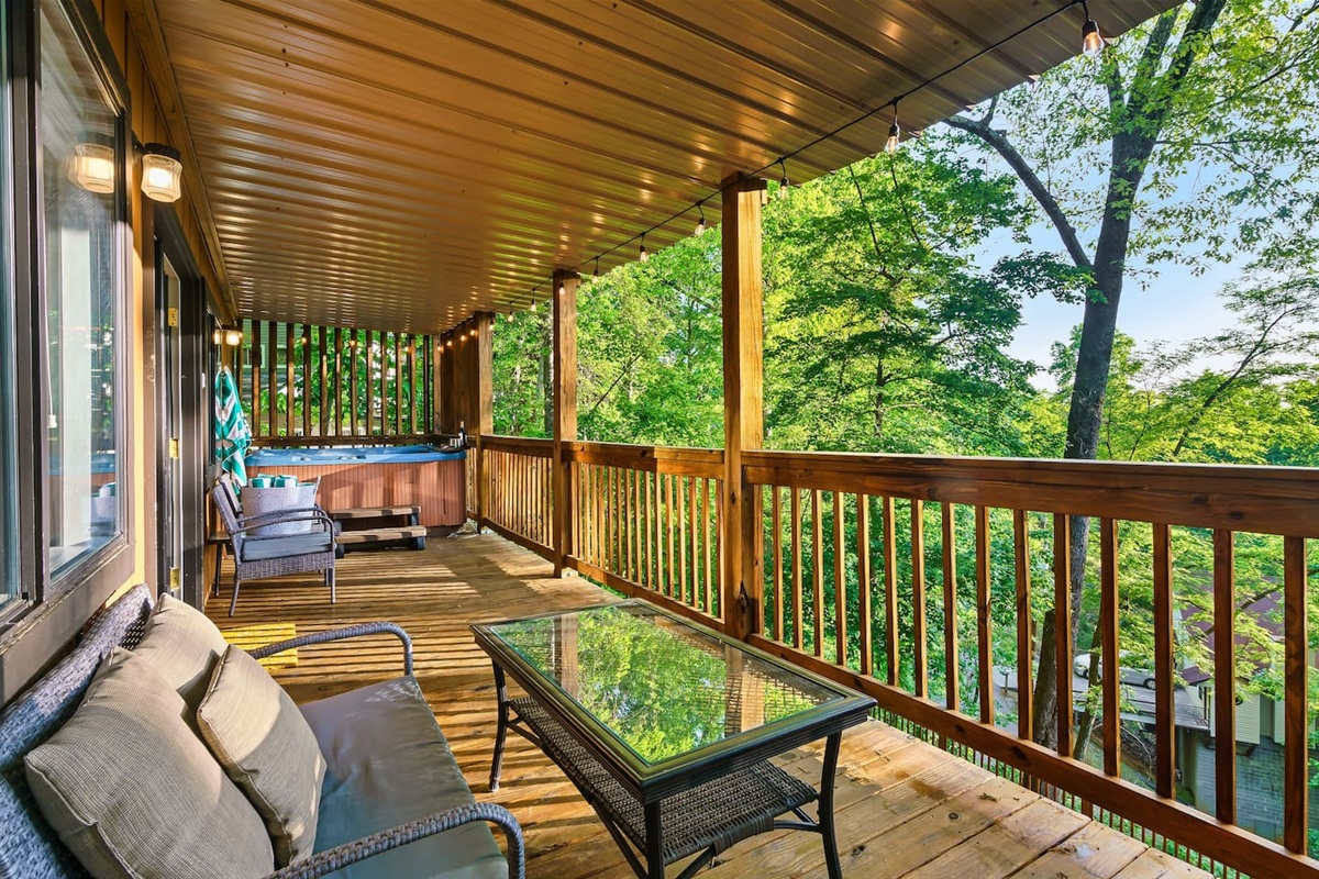 The main level, covered porch includes hot tub, seating area, and propane grill.