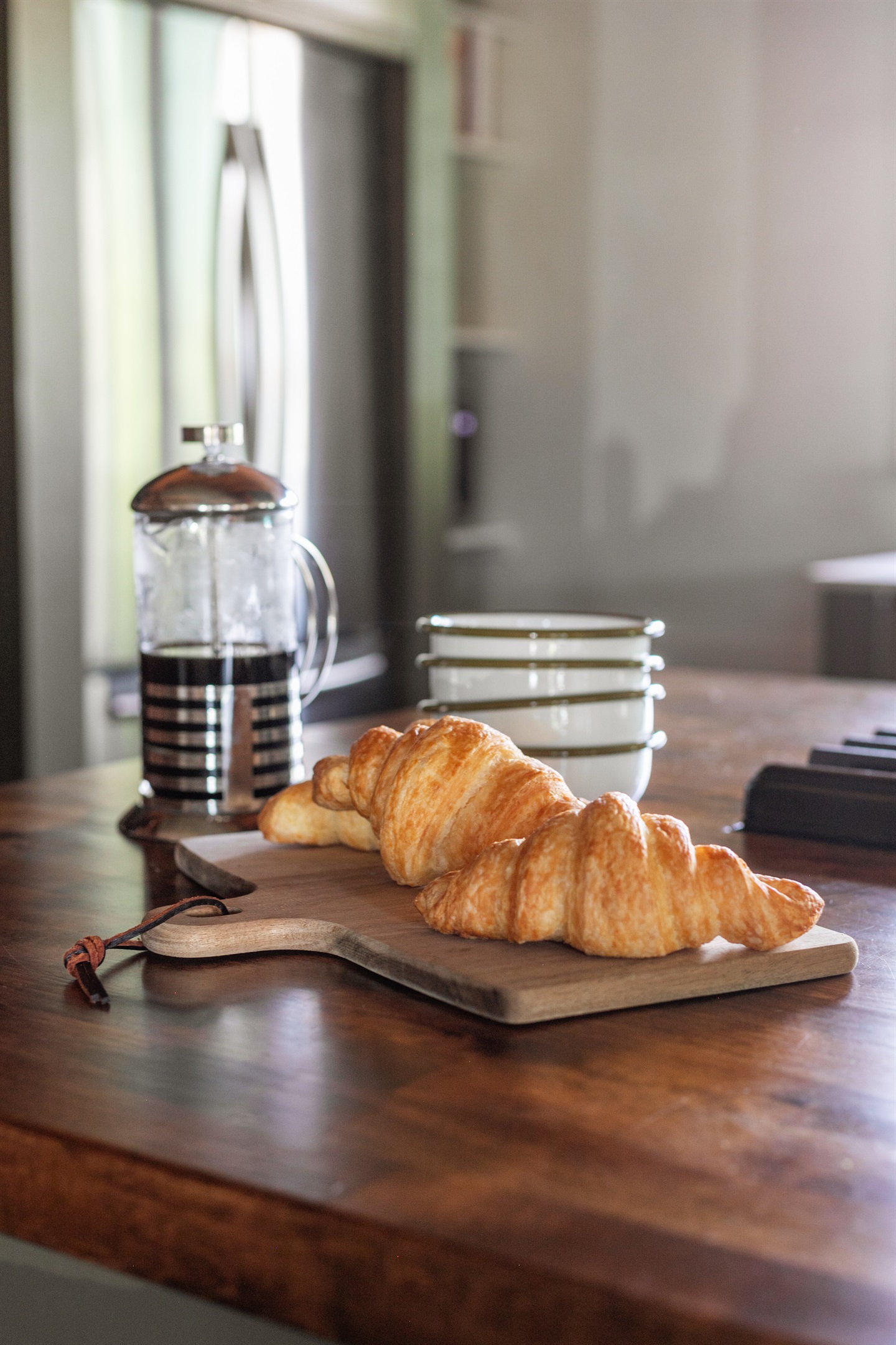 Morning begins at the island, where a French press and fresh croissant wait alongside simple, modern dishware. It’s a space that feels both stylish and welcoming — a place to pause, sip coffee, and ease into the day before the bustle begins.