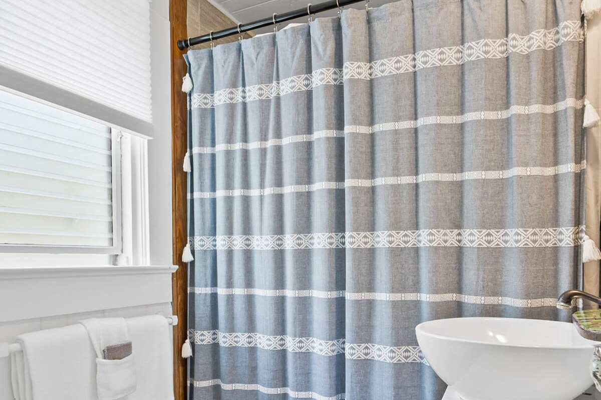 The en-suite bathroom sits just off the bedroom, with a walk-in shower behind the curtain and warm wood underfoot. Towels are provided, and that long hot shower after a day in the salt is honestly the real luxury.